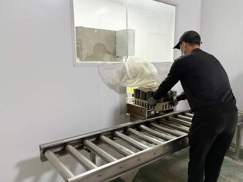 自动化设备将搅拌好的培养料灌入一个个塑料袋内,随着机器转动,食用菌